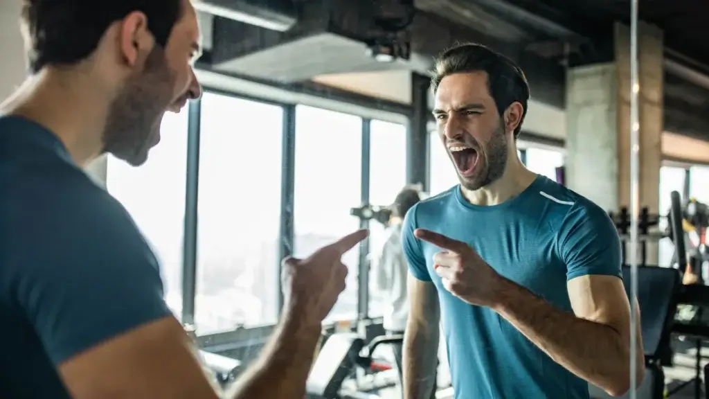 Man in blue athletic shirt yelling at his mirror reflection, showing inner conflict and emotional struggle