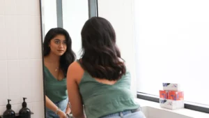 A woman looking at herself in the mirror, practicing self-awareness and emotional intelligence, reflecting on her thoughts and feelings