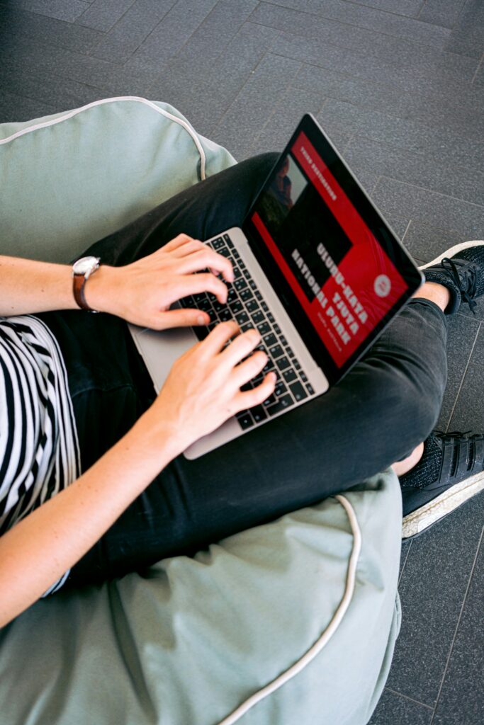 Person working remotely on a laptop, comfortably seated on a beanbag chair indoors, engaging in self-development tools like blogs